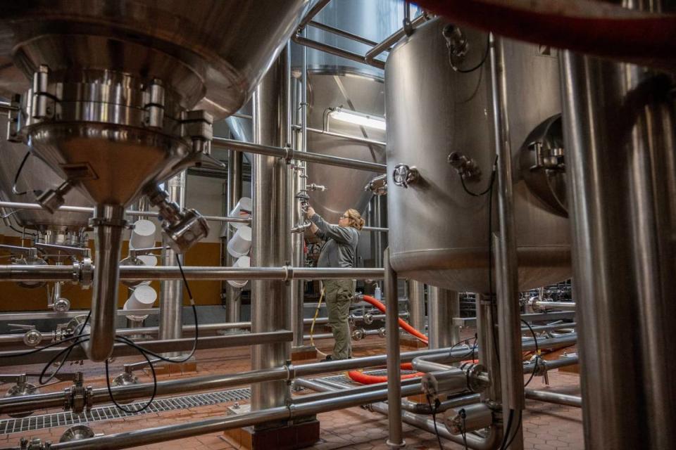 A technician adjusts a valve near the row of fermentation tanks at Boulevard.