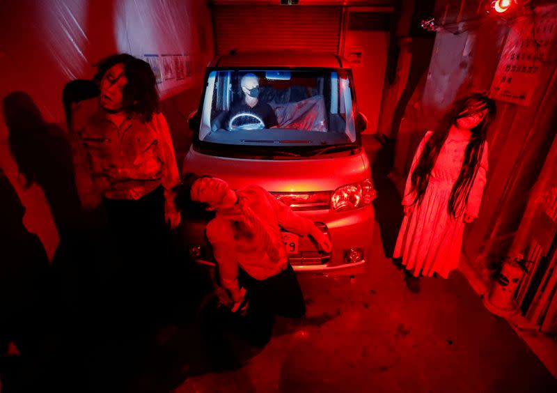 Actors dressed as zombies or ghouls perform during a drive-in haunted house show by Kowagarasetai, in Tokyo