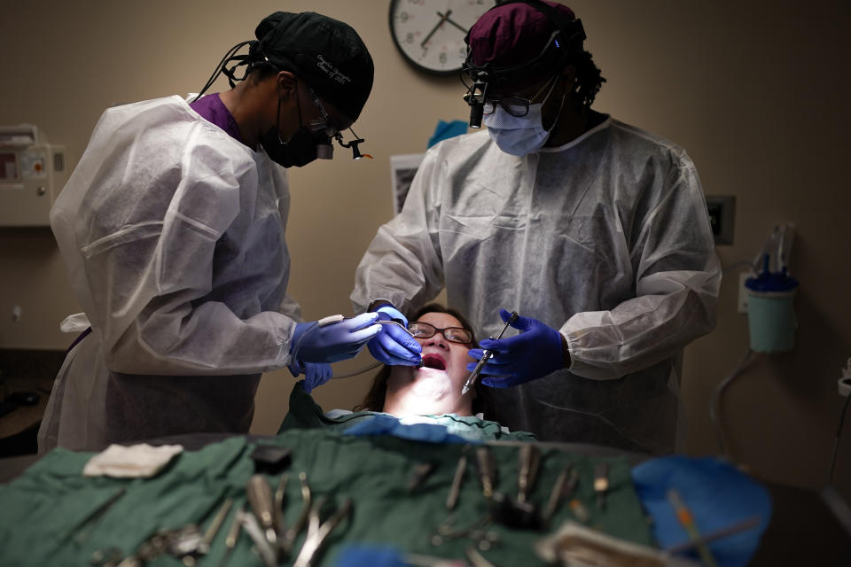 Cindy Clemons, center, receives dental care from Meharry Medical College School of Dentistry third-year student Onyeka Oguagha, left, and oral surgery resident Matthew Moore, right, Tuesday, Sept. 12, 2023, in Nashville, Tenn. Clemons was able to receive treatment after an expansion of the state's Medicaid program. (AP Photo/George Walker IV)