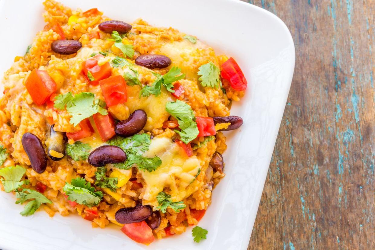 One pot Mexican rice and chicken casserole on a white rectangular plate on rustic wood table