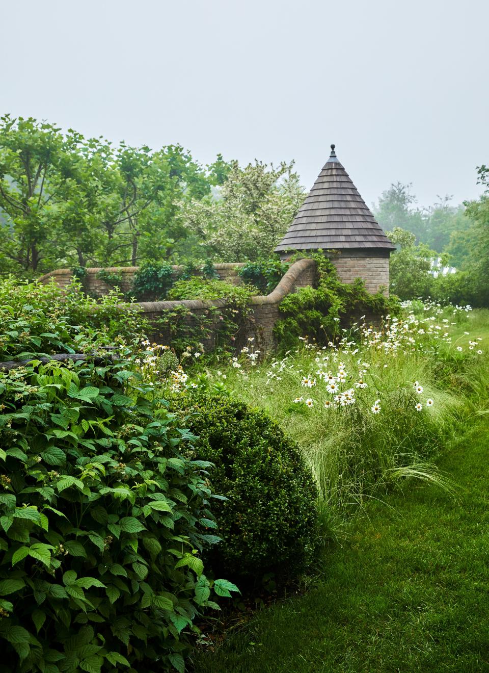 A thicket of daisies surrounds a garden wall anchored by a shingle-roofed turret.
Sittings Editor: Miranda Brooks
