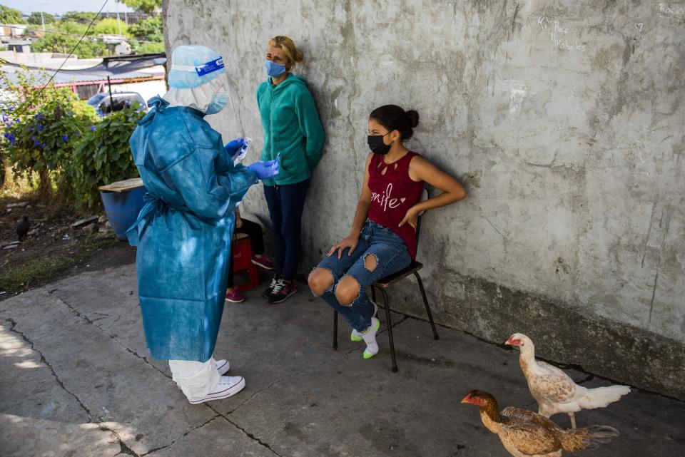 A healthcare worker prepares to test a teenager for COVID-19, on the outskirts of Montevideo, Uruguay, Thursday, March 18, 2021. Uruguay is facing a steep rise in new coronavirus infections. (AP Photo/Matilde Campodonico)