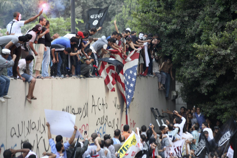 Protesters destroy an American flag pulled down from the U.S. embassy in Cairo, Egypt, Tuesday, Sept. 11, 2012. Egyptian protesters, largely ultra conservative Islamists, have climbed the walls of the U.S. embassy in Cairo, went into the courtyard and brought down the flag, replacing it with a black flag with Islamic inscription, in protest of a film deemed offensive of Islam. (AP Photo/Mohammed Abu Zaid)