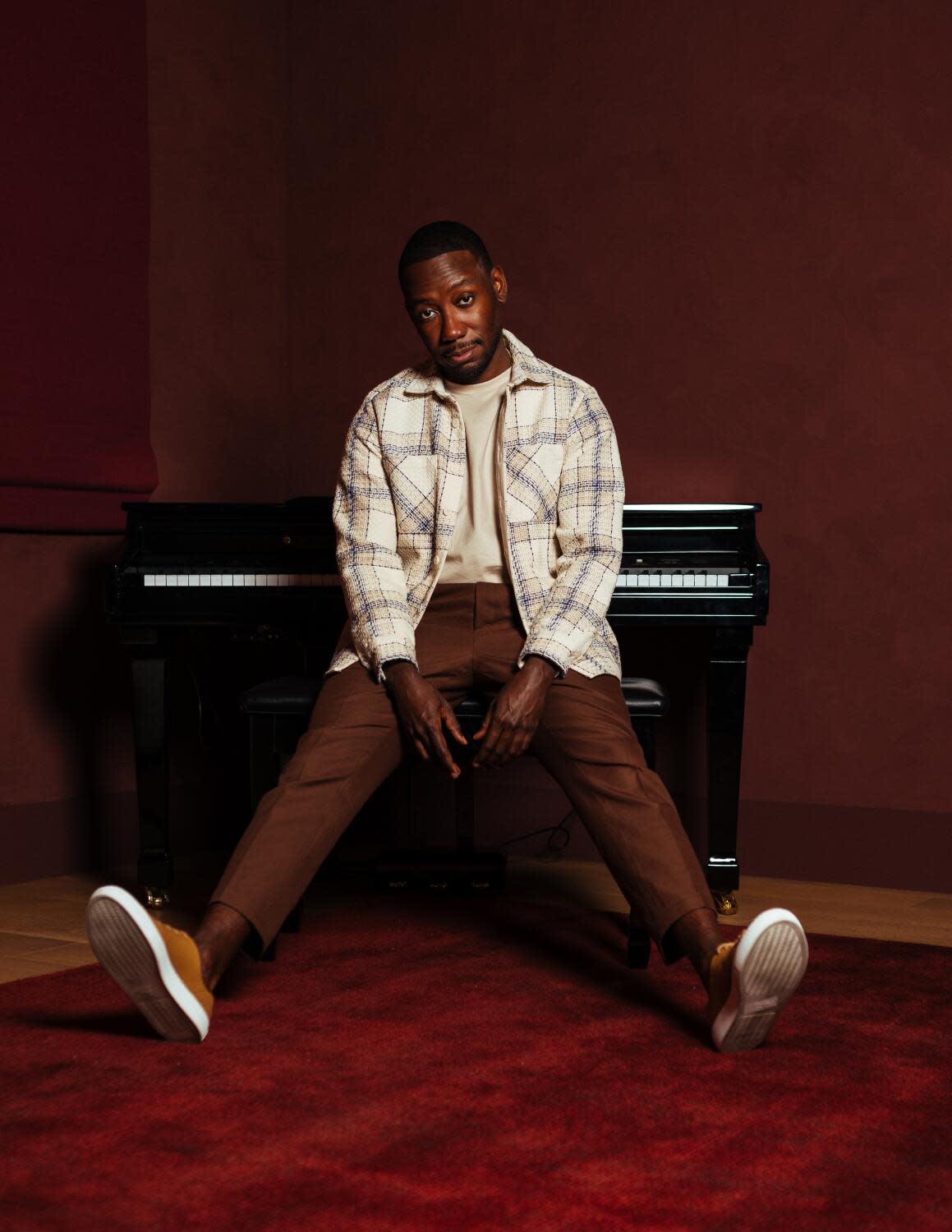 Lamorne Morris sits with a piano to his back for a portrait.