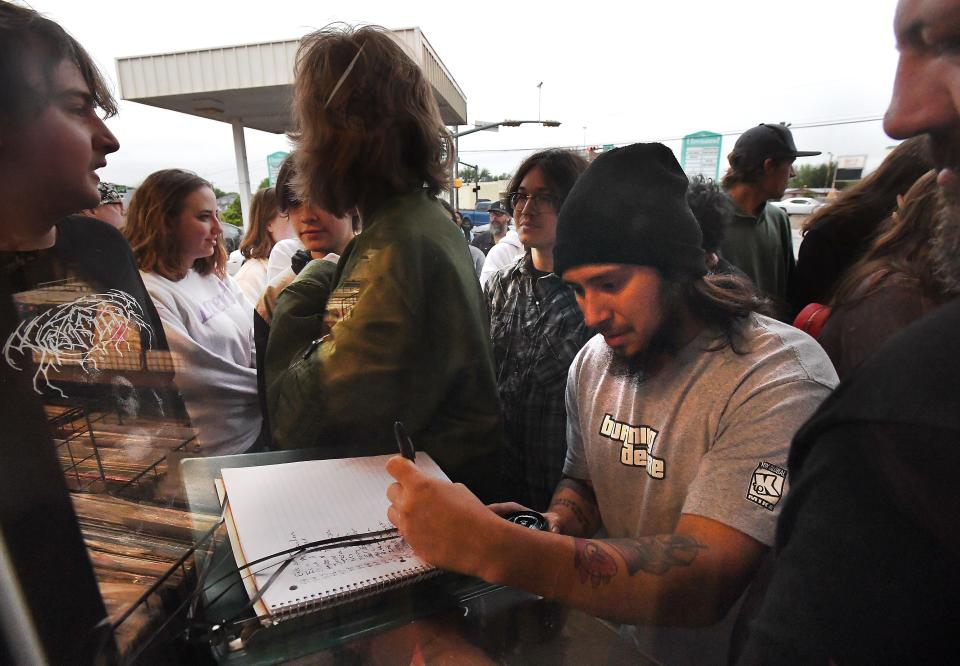 Customers are seen through the store glass as they sign the buy list for Record Store Day Saturday morning outside of The Record Guys in Abilene. The day of special releases attracted vinyl fans from across the Big Country and international customers who phoned in.