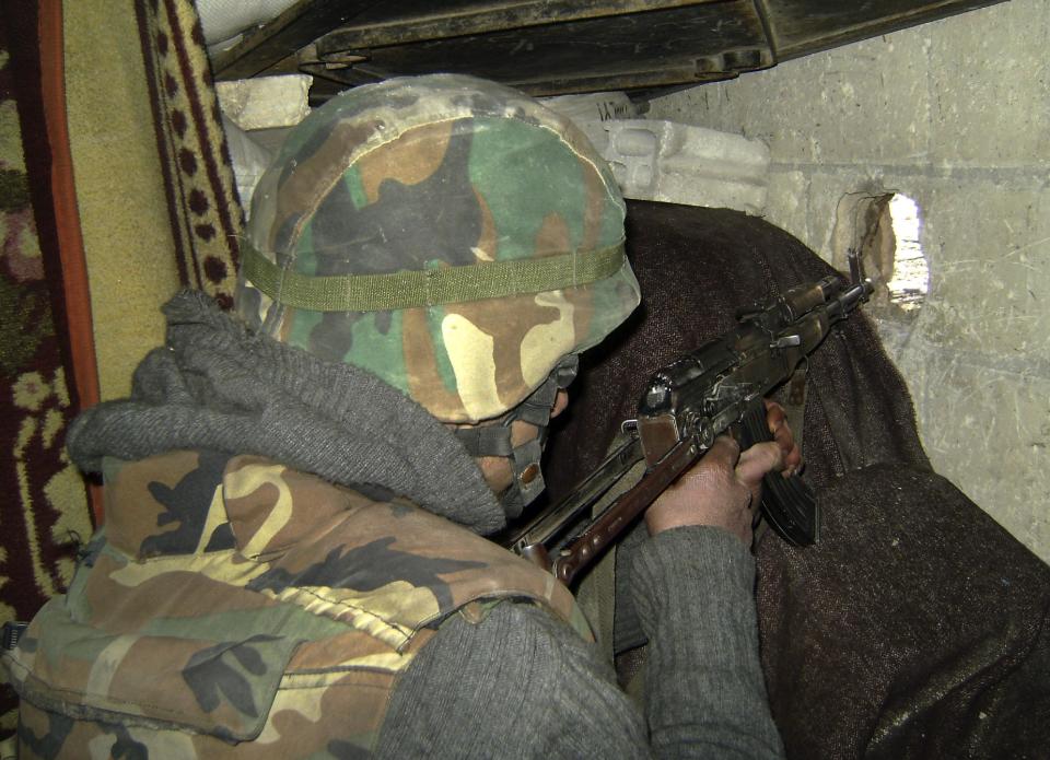 In this photo released by the Syrian official news agency SANA, a Syrian army soldier holds his automatic weapon and takes his position, in the central city of Homs, Syria, Tuesday, Feb. 4, 2014. Since it began with largely peaceful protests in March 2011, the Syrian conflict has killed more than 130,000 people, forced almost a third of the country's prewar population of 23 million from their homes, and inflamed sectarian tensions that have jolted the entire Middle East. (AP Photo/SANA)