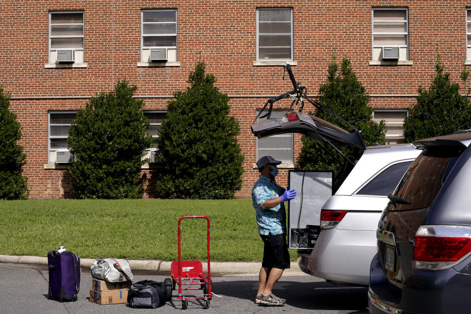 A parent packs a student's belongings at Ehringhaus dormitory following a cluster of COVID-19 cases on campus at the University of North Carolina in Chapel Hill, N.C., Tuesday, Aug. 18, 2020. The university announced that it would cancel all in-person undergraduate learning starting on Wednesday causing some students to pack and leave. (AP Photo/Gerry Broome)