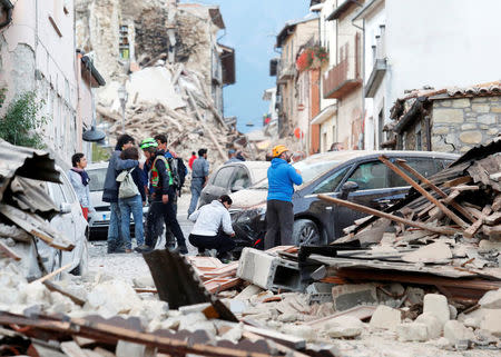 Personas inspeccionan los daños causados por un terremoto, en Amatrice, Italia. 24 de agosto de 2016. Un devastador terremoto sacudió el miércoles varias localidades del centro de Italia, dejando al menos 120 personas muertas, residentes atrapados bajo los escombros y un número indeterminado de desaparecidos. REUTERS/Remo Casilli