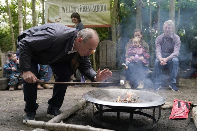 Sir Ed Davey blowing on a firepit during a visit to Willow Forest School, in Guildford, Surrey