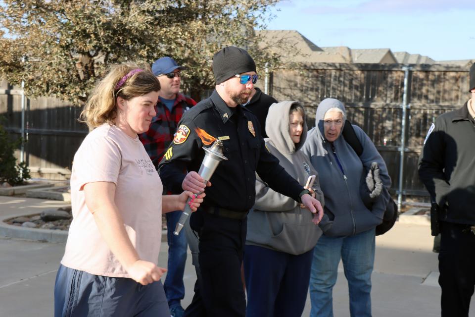 Lindsey Fowler and Sgt Sheldon West carry the Special Olympics torch to the pool's edge to mark the start of the annual Special Olympics Polar Plunge held at Amarillo Town Club on Hillside Saturday morning.