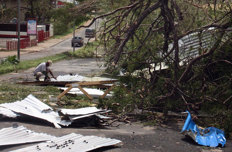 A local resident kneels near debris on a street near damaged homes in Port Vila