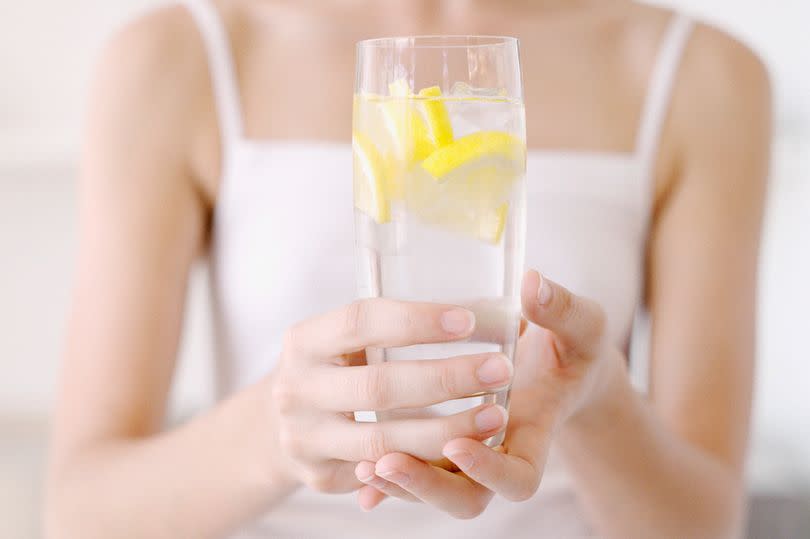 Woman holding glass of lemon water