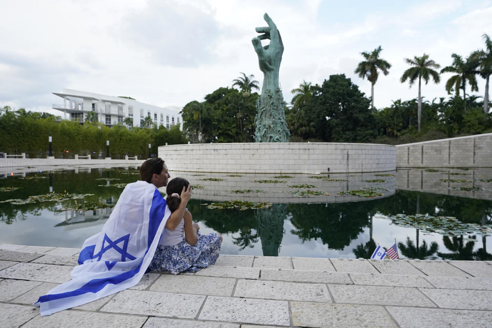 FILE - Draped in an Israeli flag, Elinor Ben David, left, hugs her daughter Liel Abissidan, 8, as they wait for a rally in support of Israel to start, at the Holocaust Memorial Miami Beach, Oct. 10, 2023, in Miami Beach, Fla. An estimated 525,000 Jews live in Miami's metropolitan area according to the American Jewish Population Project at Brandeis University. In South Florida, rabbis and community leaders are pushing their congregations to call their lawmakers and insist they back Israel as it ramps up its offensive. (AP Photo/Wilfredo Lee, File)