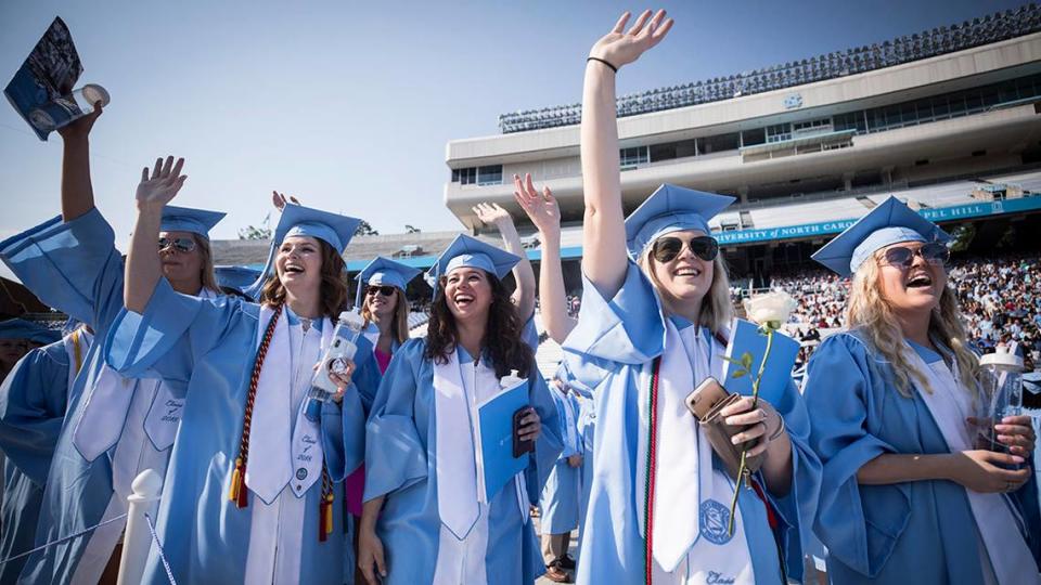 Students wave to their friends as they file onto the field at Kenan Memorial Stadium for UNC-Chapel Hill’s 2018 spring commencement ceremony on Sunday, May 28, 2018.