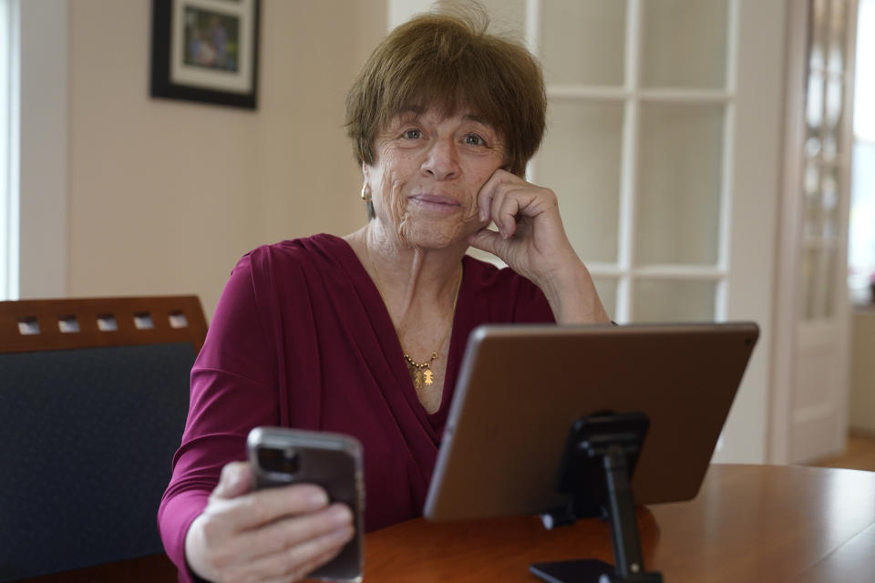 Pat Olken, of Sharon, Mass., sits for a photograph while using the Otter app on her iPhone at her home, in Sharon, Thursday, April 14, 2022. People with hearing loss have adopted technology to navigate the world. (AP Photo/Steven Senne)