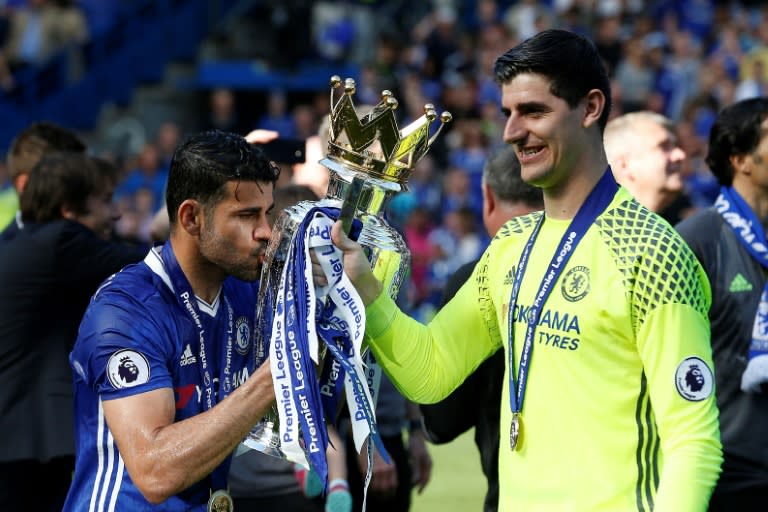Chelsea's striker Diego Costa kisses the English Premier League trophy, held by Chelsea's goalkeeper Thibaut Courtois (R), as players celebrate their league title win at the end of the Premier League football match against Sunderland May 21, 2017