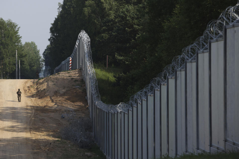 FILE - A Polish border guard patrols the area of a newly built metal wall on the border between Poland and Belarus, near Kuznice, Poland, June 30, 2022. Human rights activists in Poland say a group of 30 migrants including small children and seeking asylum has been stuck across Poland's border wall with Belarus for three days. A representative of Poland's ombudsman's office visited and talked to the group on Sunday May 28, 2023, but said the decision belongs to the authorities. (AP Photo/Michal Dyjuk, File)
