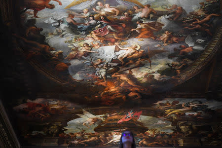 A gallery assistant poses beside a fresco during the reopening of The Painted Hall, Old Royal Navy College in London, Britain, March 20, 2019. REUTERS/Dylan Martinez