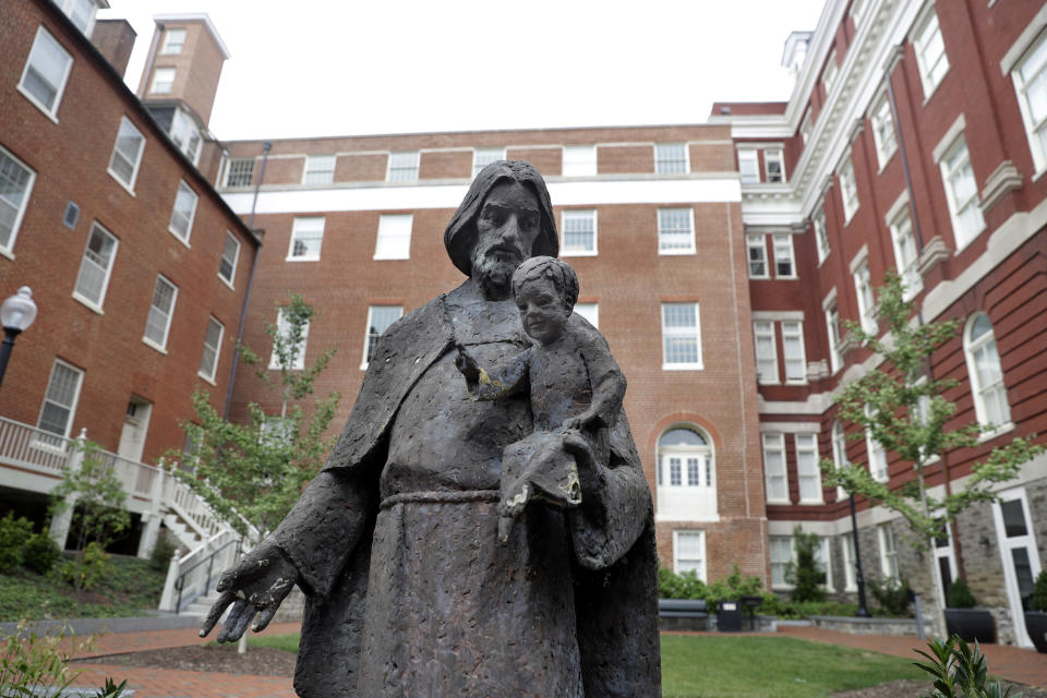 FILE- In this Sept. 1, 2016 file photo, a Jesuit statue is seen in front of Freedom Hall, formerly named Mulledy Hall, on the Georgetown University campus in Washington. Georgetown University and two theological seminaries have announced plans for reparations to benefit descendants of the enslaved people who played a role in the institutions' success. At least 56 universities have joined a University of Virginia-led consortium, Universities Studying Slavery, to explore their ties to slavery and share research and strategies. (AP Photo/Jacquelyn Martin, File)