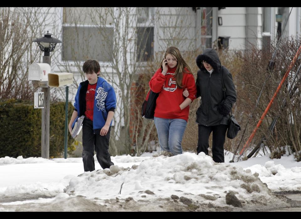 A woman and her children walk down a back street near Chardon High School in Chardon, Ohio Monday, Feb. 27, 2012. A gunman opened fire inside the high school's cafeteria at the start of the school day Monday, killing three students and wounding two others, officials said. Special Agent Vicki Anderson said Monday the shooter was taken into custody near his car about half a mile (one kilometer) away from the high school. (AP Photo/Mark Duncan)