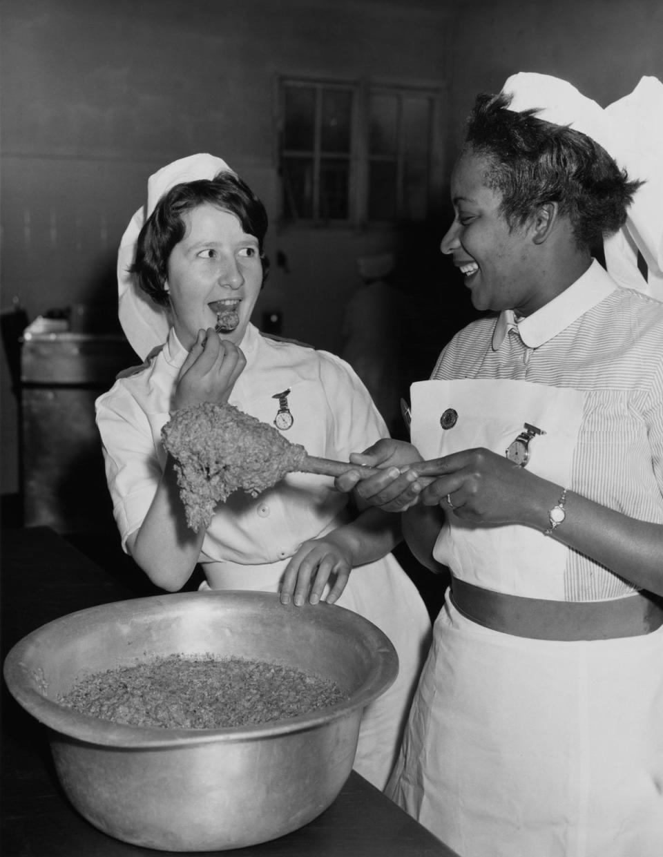 Irish nurse Theresa McHugh tastes the Christmas pudding mixture as Barbadian nurse Julien laughs at Wembley Hospital in London (Getty Images)