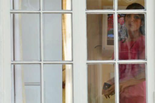 Jill Kelley looks out the window of her home as Gen. David Petraeus is seen on the television in the background on November 13, in Tampa, Florida. Top US commander in Afghanistan General John Allen was placed under investigation after FBI agents probing the scandal involving former CIA director Petraeus stumbled on messages Allen sent to Kelley