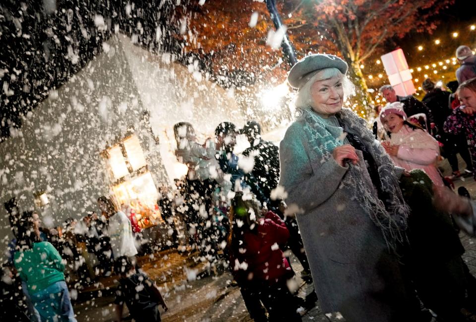 Peggy Drinkard walks through the artificial snow during the Dickens Downtown celebration on Main Ave. in Northport Wednesday, Dec. 5, 2023.