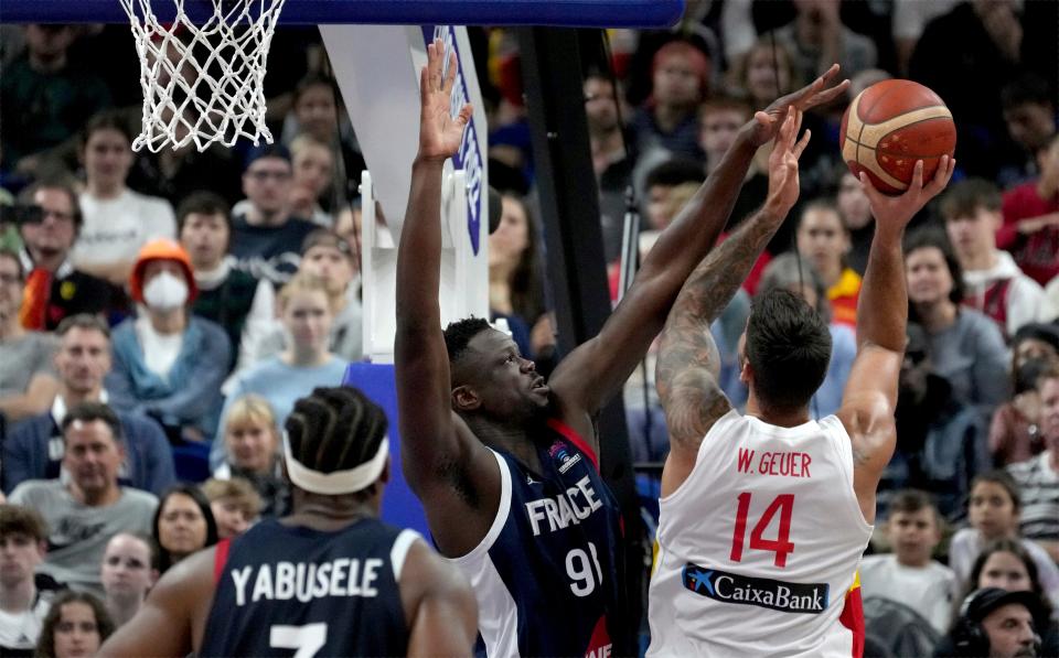 Moustapha Fall of France, center, is challenged by Spain's Willy Hernangomez, right, during the Eurobasket final basketball match between Spain and France in Berlin, Germany, Sunday, Sept. 18, 2022. (AP Photo/Michael Sohn)