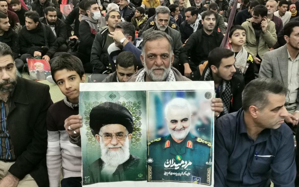 A man holds portraits of Supreme Leader Ayatollah Ali Khamenei and slain top Iranian commander Qasem Soleimani during the ceremonies marking the anniversary of his killing in the Iranian capital Tehran on Jan 3
