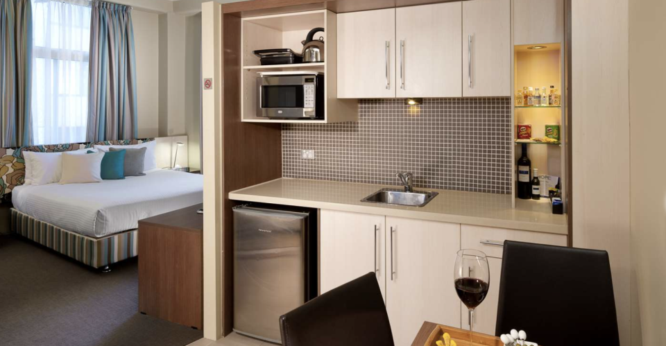 A room at the Best Western hotel featuring kitchenette, dining table and a glass of red wine