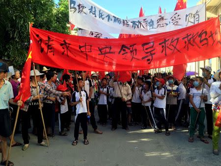 Villagers carry banners which read "Plead the central government to help Wukan" (in red) and "Wukan villagers don't believe Lin Zuluan took bribes" during a protest in Wukan, China's Guangdong province June 22, 2016. REUTERS/James Pomfret