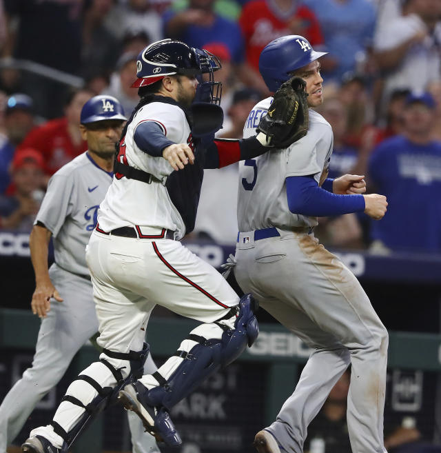 Atlanta Braves catcher Travis d'Arnaud, front left, tags out Los Angles Dodgers' Freddie Freeman, right, in a rundown between third and home on a fielder's choice during the sixth inning of a baseball game Sunday, June 26, 2022, in Atlanta. (Curtis Compton/Atlanta Journal-Constitution via AP)