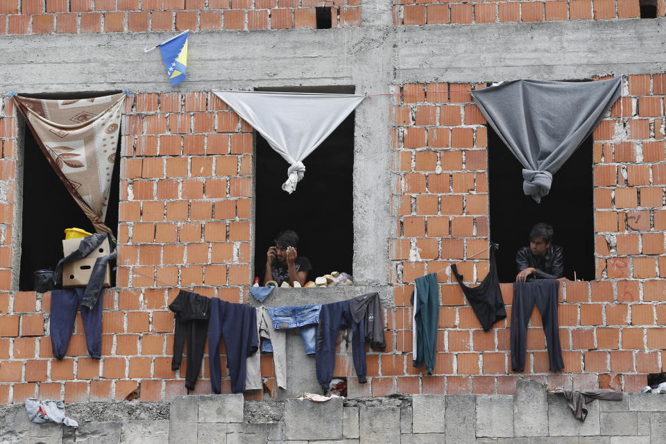 In this photo taken on Tuesday, Aug. 14, 2018, migrants stand by a window in a makeshift migrant camp in Bihac, 450 kms northwest of Sarajevo, Bosnia. Impoverished Bosnia must race against time to secure proper shelters for at least 4,000 migrants and refugees expected to be stranded in its territory during coming winter. The migrant trail shifted toward Bosnia as other migration routes to Western Europe from the Balkans were closed off over the past year. (AP Photo/Amel Emric)