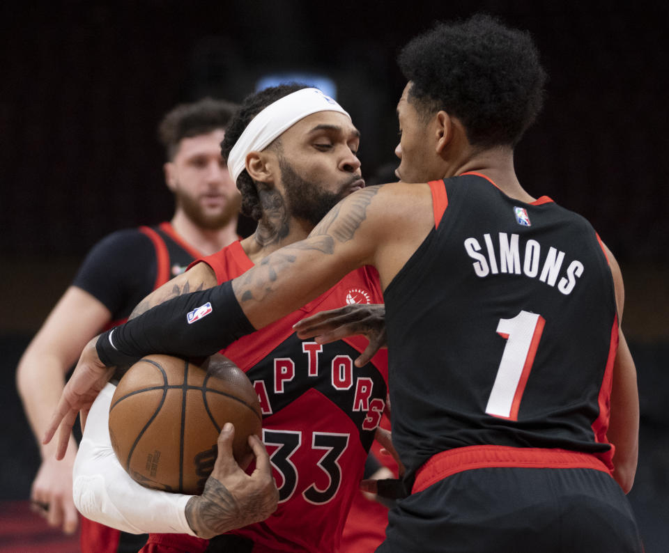 Toronto Raptors guard Gary Trent Jr. (33) battles with Portland Trail Blazers guard Anfernee Simons (1) during first-half NBA basketball game action in Toronto, Sunday Jan. 23, 2022. (Frank Gunn/The Canadian Press via AP)