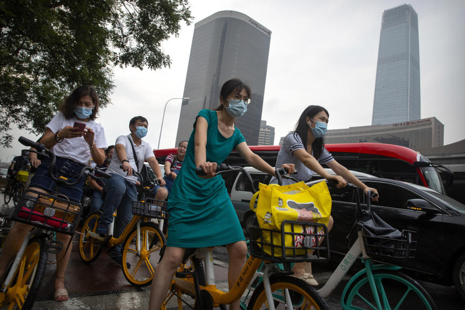 People wearing face masks to protect against the coronavirus wait at an intersection in the central business district in Beijing, Friday, July 31, 2020. China is tightening travel restrictions in the capital of Xinjiang, where more than a hundred new cases were reported Friday. (AP Photo/Mark Schiefelbein)