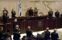 FILE - German Chancellor Angela Merkel, top center, receives a standing ovation after she addresses the Knesset, Israel's parliament during a special session in Jerusalem, March 18, 2008. Merkel has been credited with raising Germany’s profile and influence, helping hold a fractious European Union together, managing a string of crises and being a role model for women in a near-record tenure. Her designated successor, Olaf Scholz, is expected to take office Wednesday, Dec. 8, 2021. (AP Photo/Sebastian Scheiner, Pool, File)