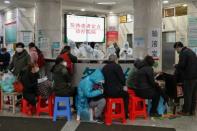 People wait to see medical staff (back) in protective clothing at Wuhan Red Cross Hospital, in the Chinese city at the epicentre of the coronavirus epidemic