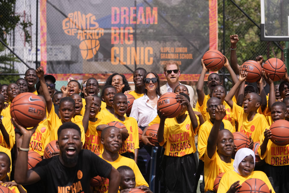 Prince Harry and Meghan, center, pose for a photograph with children during the Giant of Africa Foundation at the Dream Big Basketball clinic in Lagos Nigeria, Sunday, May 12, 2024. Prince Harry and his wife Meghan are in Nigeria to champion the Invictus Games, which Prince Harry founded to aid the rehabilitation of wounded and sick servicemembers and veterans. (AP Photo/Sunday Alamba)