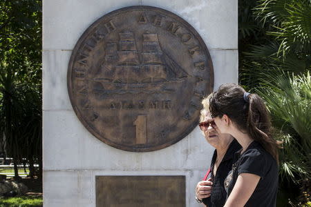 Women walk past a replica of a one drachma coin in Athens, Greece, July 2, 2015. REUTERS/Marko Djurica