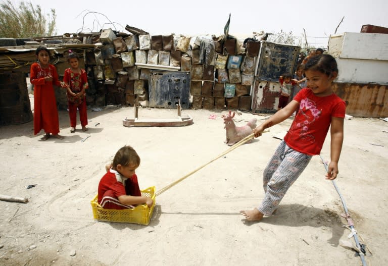 Children of impoverished Iraqi families play outside their homes, which are made up of scrap metal, in the holy Iraqi city of Najaf on July 19, 2015