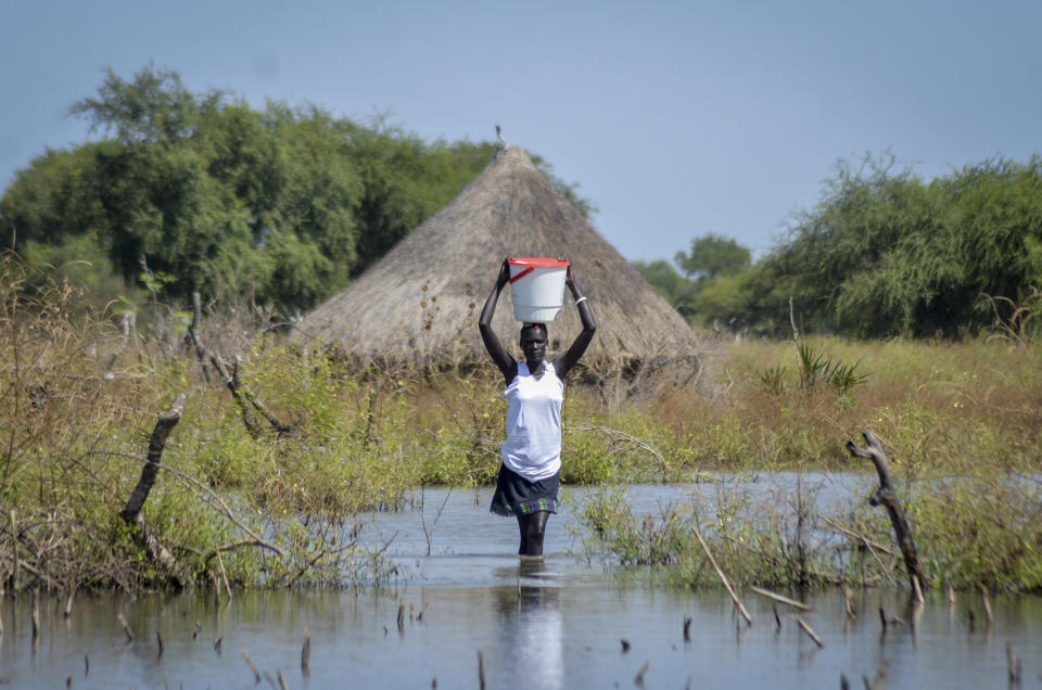 FILE - A woman carries a bucket on her head as she wades through floodwaters in the village of Wang Chot, Old Fangak county, Jonglei state, South Sudan on Nov. 26, 2020. A petition to stop the revival of the 118-year-old Jonglei Canal project in South Sudan, started by one of the country's top academics, is gaining traction in the country, with the waterway touted as a catastrophic environmental and social disaster for the country's Sudd wetlands. (AP Photo/Maura Ajak, File)