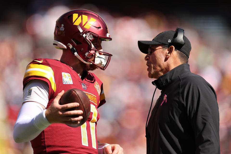 LANDOVER, MARYLAND - OCTOBER 09: Carson Wentz #11 of the Washington Commanders talks with head coach Ron Rivera during the first half against the Tennessee Titans at FedExField on October 09, 2022 in Landover, Maryland. (Photo by Scott Taetsch/Getty Images)