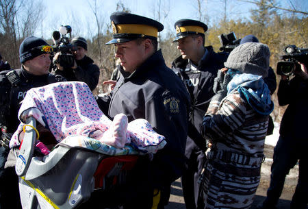 A mother and her child are taken into custody by Royal Canadian Mounted Police (RCMP) officers after crossing U.S.-Canada border into Hemmingford, Quebec, Canada February 20, 2017. REUTERS/Christinne Muschi