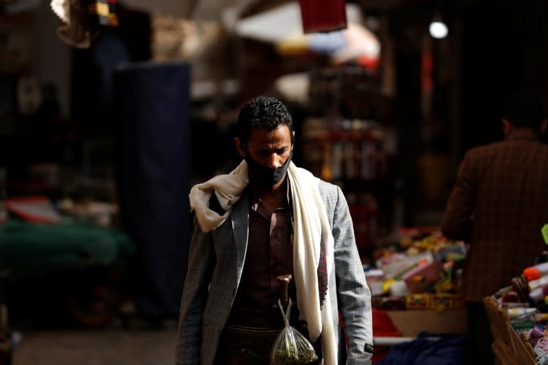 A man wearing a protective mask walks in the old quarter of Sanaa