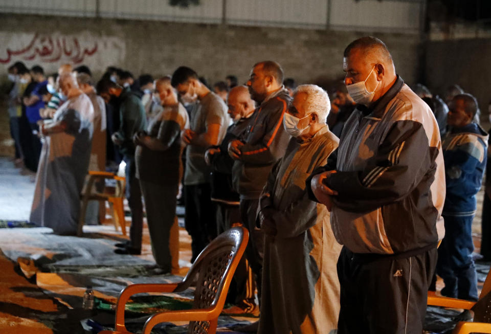 People, some wearing masks to help prevent the spread of the coronavirus, pray the evening prayer during the Muslim holy fasting month of Ramadan, outside a mosque in Gaza City, Tuesday, April 20, 2021. More than a year into the coronavirus pandemic, the worst fears are now coming true in the crowded, blockaded Gaza Strip: A sudden surge in infections and deaths is threatening to overwhelm hospitals weakened by years of conflict and Israeli border closures. (AP Photo/Adel Hana)