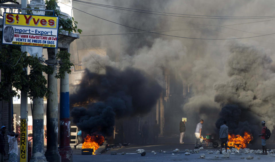 Burning tires and large rocks serve as barricades blocking a road on the third day of a strike and of countrywide protests over allegations of government corruption, in Port-au-Prince, Haiti, Tuesday, Nov. 20, 2018. Demonstrators are calling for the president to resign for not investigating allegations of corruption in the previous government over a Venezuelan subsidized energy program, Petrocaribe. (AP Photo/Dieu Nalio Chery)