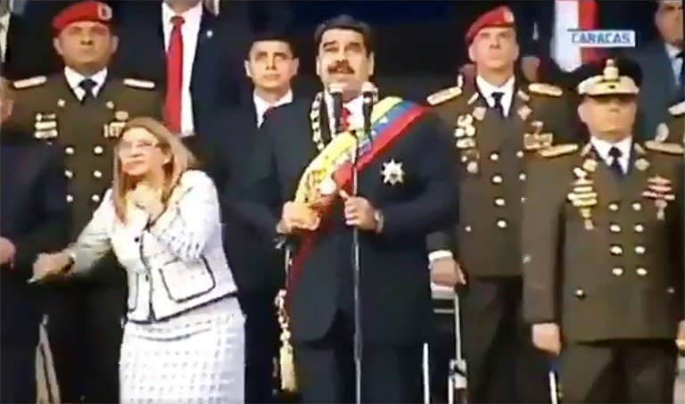 A screengrab taken from a handout video released by Venezuelan Television (VTV) showing Venezuelan President Nicolas Maduro (C), his wife Cilia Flores (L) and military authorities reacting to an explosion during the August 4 ceremony