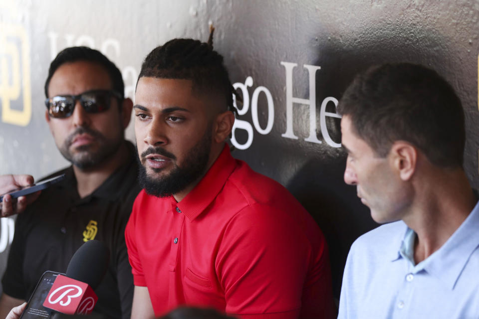 San Diego Padres' Fernando Tatis Jr., center, speaks to the media about his 80 game suspension from baseball after testing positive for Clostebol, a performance-enhancing substance in violation of Major League Baseball's Joint Drug Prevention and Treatment Program, Tuesday, Aug. 23, 2022, in San Diego. (AP Photo/Derrick Tuskan)