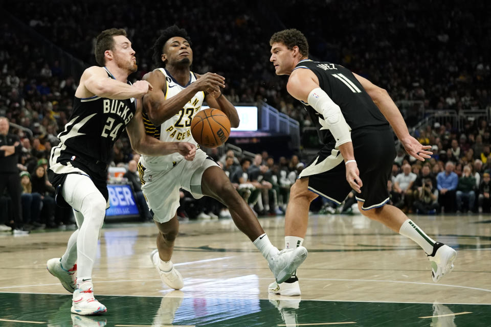 Indiana Pacers' Aaron Nesmith, middle, drives to the basket between Milwaukee Bucks' Pat Connaughton and Brook Lopez during the first half of an NBA basketball game, Monday, Jan. 16, 2023, in Milwaukee. (AP Photo/Aaron Gash)