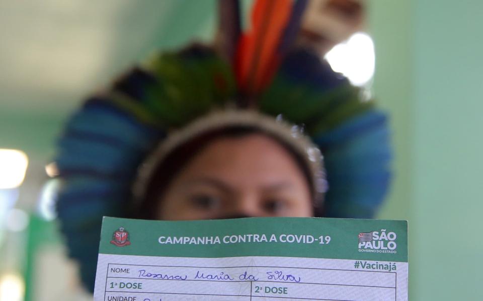 An Indigenous woman shows her vaccination card after receiving the second dose of Sinovac's CoronaVac vaccine at a health station, in Guarulhos, near Sao Paulo - Reuters